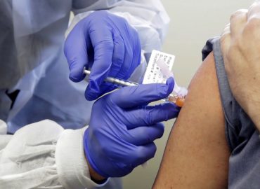 FILE - In this March 16, 2020, file photo, Neal Browning receives a shot in the first-stage safety study clinical trial of a potential vaccine for COVID-19, the disease caused by the new coronavirus, at the Kaiser Permanente Washington Health Research Institute in Seattle. The vaccine by Cambridge, Massachusetts-based Moderna Inc., generated antibodies similar to those seen in people who have recovered from COVID-19 in a study of volunteers who were given either a low or medium dose. (AP Photo/Ted S. Warren, File)