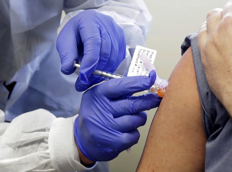 FILE - In this March 16, 2020, file photo, Neal Browning receives a shot in the first-stage safety study clinical trial of a potential vaccine for COVID-19, the disease caused by the new coronavirus, at the Kaiser Permanente Washington Health Research Institute in Seattle. The vaccine by Cambridge, Massachusetts-based Moderna Inc., generated antibodies similar to those seen in people who have recovered from COVID-19 in a study of volunteers who were given either a low or medium dose. (AP Photo/Ted S. Warren, File)